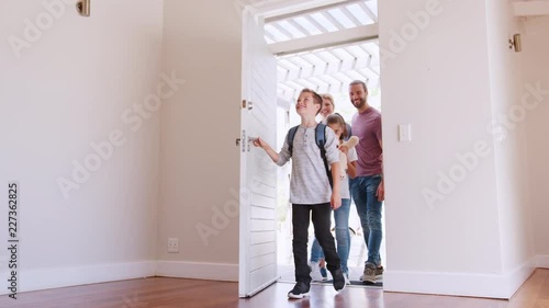 Slow Motion Shot Of Family Opening Door And Walking In Empty Lounge Of New Home photo