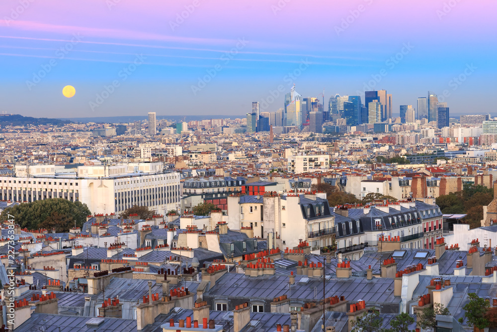 Obraz premium Aerial view from Montmartre over Paris roofs and La Defense business district with full moon at sunrise, Paris, France