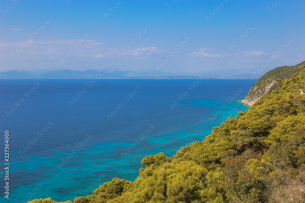 A view over the pine forest on the turquoise sea. Fantastic view of the west coast of Lefkada island, Greece, Europe. Beauty of nature concept background.