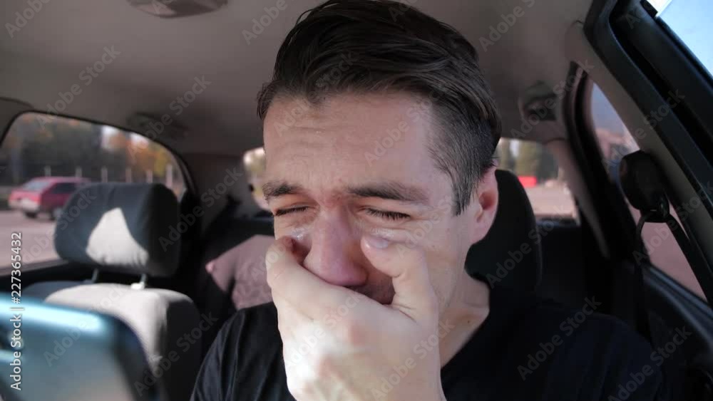 Sad desperate man reading bad sms at smatphone crying in the car Sad desperate man reading bad sms at smatphone crying in the car