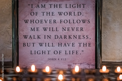 Memorial candles burning in front of a wall plaque with bible verse photo