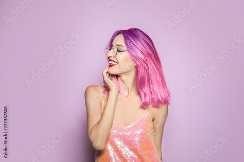 Portrait of smiling young woman with dyed straight hair on color background. Trendy hairstyle design