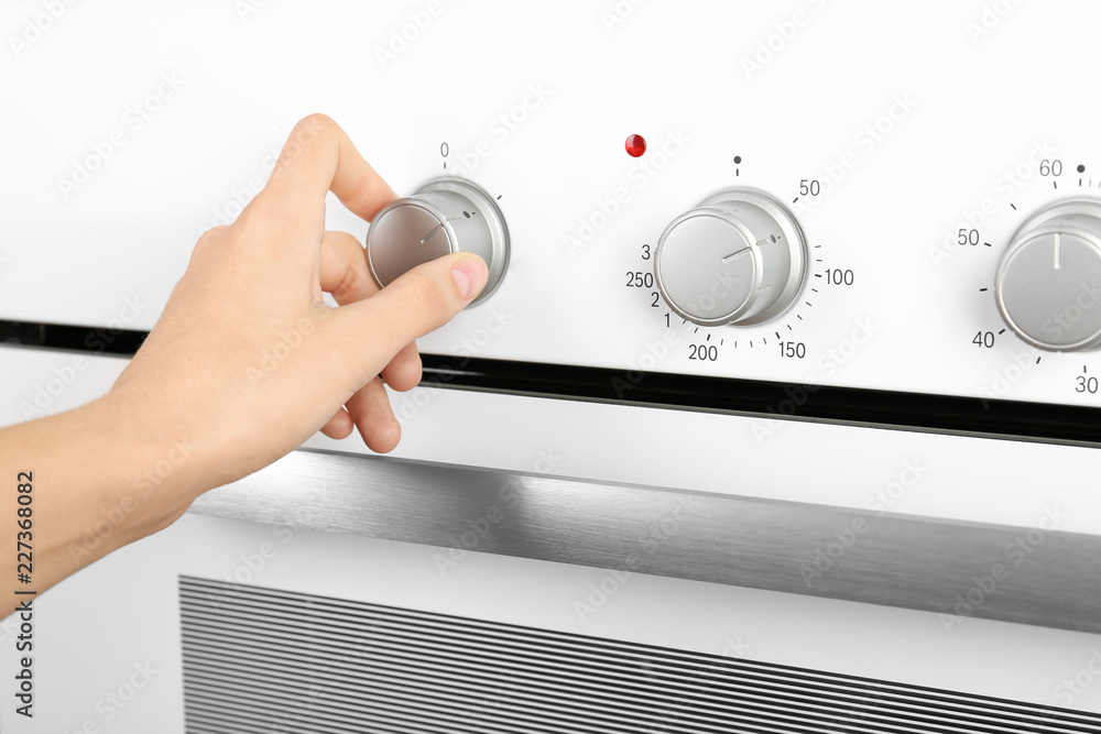 Woman adjusting electric oven, closeup. Kitchen appliance Woman adjusting electric oven, closeup. Kitchen appliance