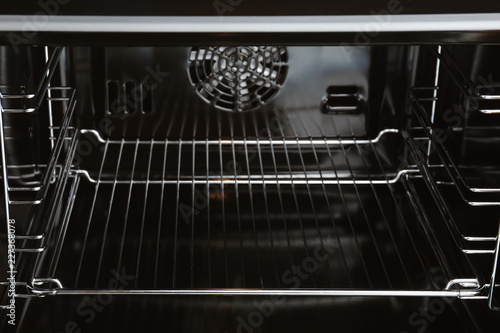 Open empty electric oven with rack, closeup. Inside view