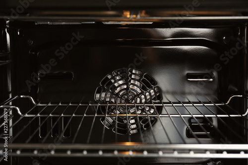 Open empty electric oven with rack, closeup. Inside view