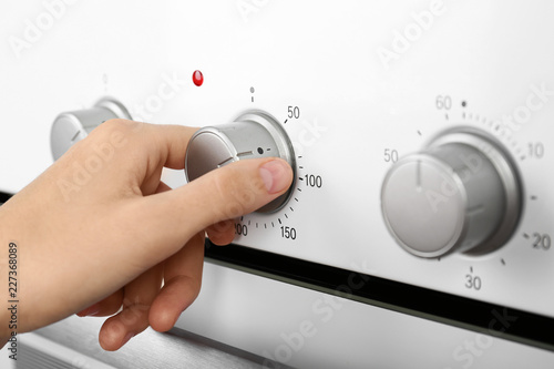 Woman adjusting electric oven, closeup. Kitchen appliance