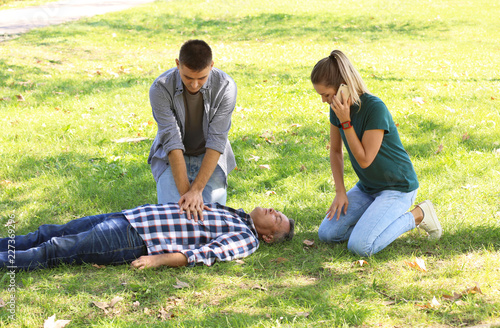 Passersby helping unconscious man outdoors. First aid photo
