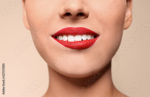 Beautiful young woman with red lips on color background, closeup