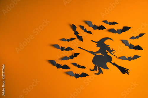 Paper bats and witch cutout on color background with space for text. Halloween decor