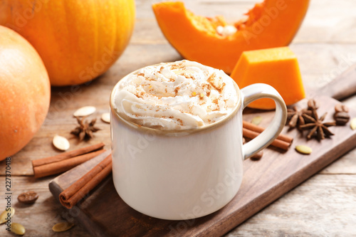 Cup with tasty pumpkin spice latte on wooden table