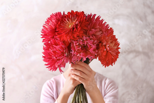 Fototapeta Naklejka Na Ścianę i Meble -  Woman hiding behind beautiful dahlia flowers on color background