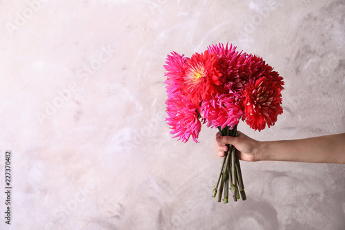 Fototapeta Naklejka Na Ścianę i Meble -  Woman holding beautiful dahlia flowers on color background. Space for text