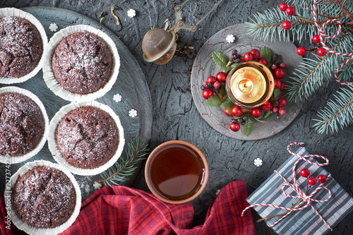 Chocolate muffins, tea cup, tea mesh on gray rustic backgrond with gift box and decorated Christmas tree twigs