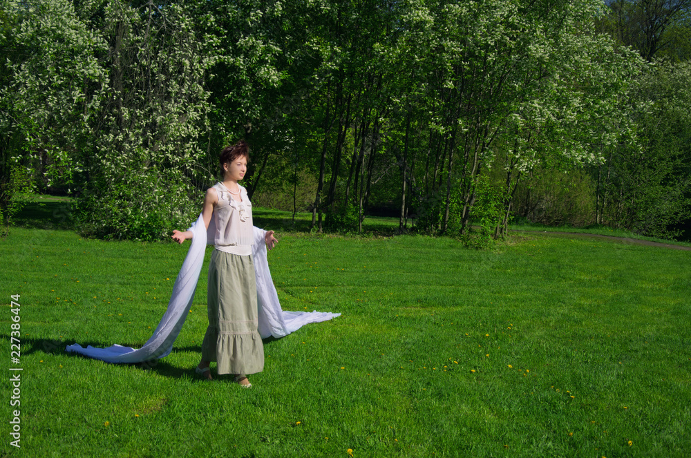 young Oriental woman walking on a green meadow on a spring day young Oriental woman walking on a green meadow on a spring day