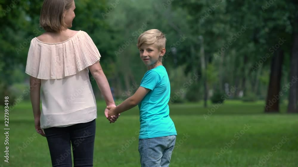 Woman and boy holding hands, walking away together, social protection concept Woman and boy holding hands, walking away together, social protection concept