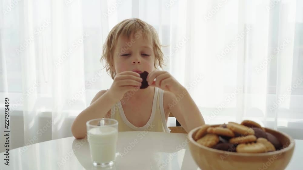 boy eating homemade cookies with milk at home kitchen boy eating homemade cookies with milk at home kitchen