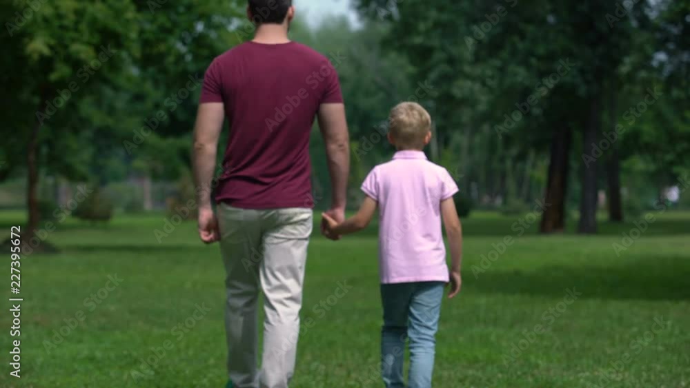 Father and boy holding hands, walking away, giving advice for son to be real man Father and boy holding hands, walking away, giving advice for son to be real man