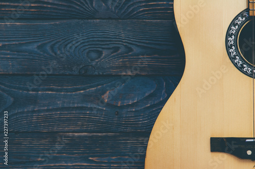 Acoustic guitar lies on a wooden textured background.