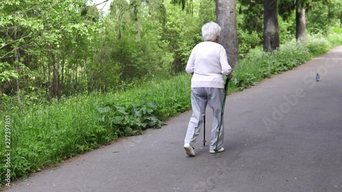 grandmother walks with Nordic walking sticks old grey photo