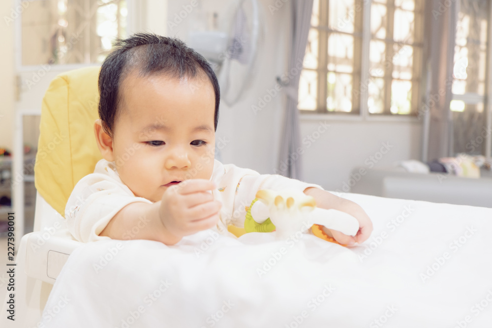 asian baby is playing a teething toy on high chair. asian baby is playing a teething toy on high chair.
