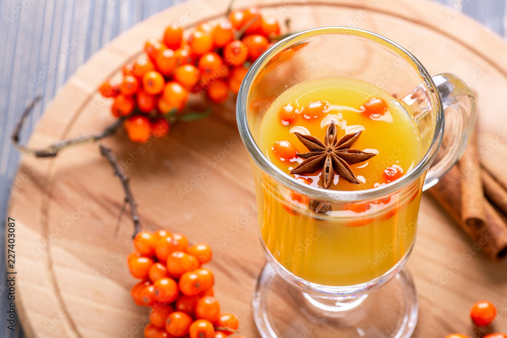 Hot beverage of sea-buckthorn berries in glass cup on wooden background. Rustic style. Hot beverage of sea-buckthorn berries in glass cup on wooden background. Rustic style.