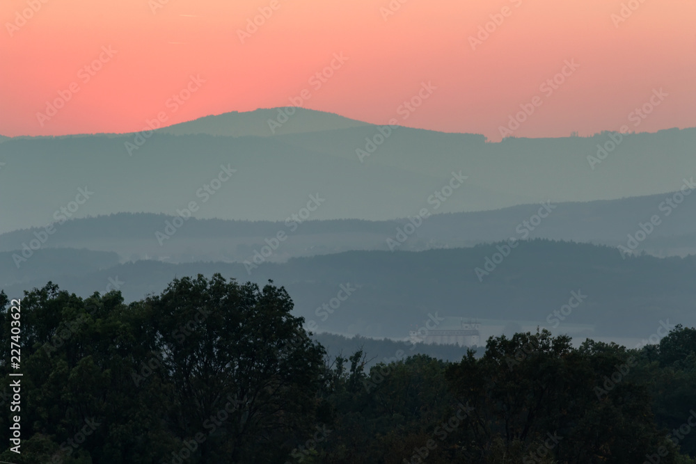Red sunset sky with hills tree silhouette