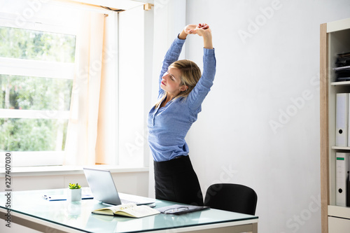 Konstfotografi Businesswoman Stretching Her Arms At Workplace
