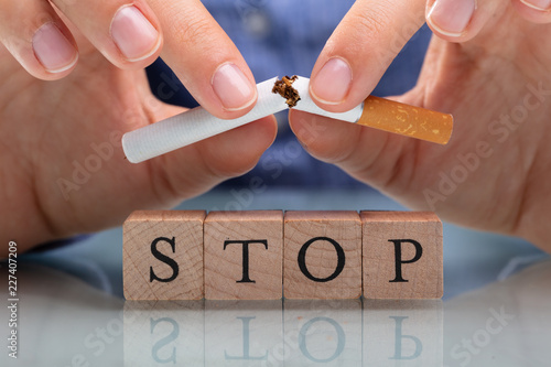 Woman Breaking Cigarette Over Stop Wooden Blocks photo