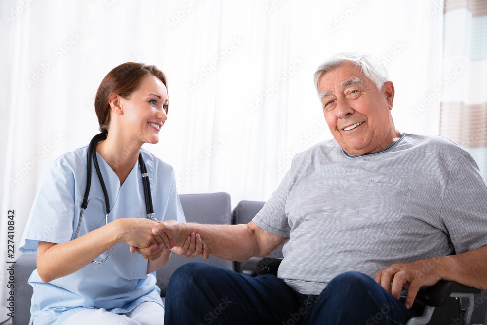 Obraz premium Senior Man Sitting On Wheelchair With Female Nurse