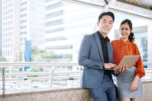 Young business man and woman use notebook laptop for work project in city.