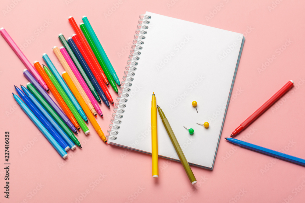 Colorful felt tip pens with blank notepad paper on pink pastel background Colorful felt tip pens with blank notepad paper on pink pastel background