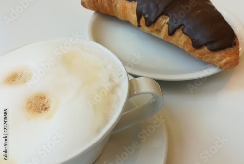 Tasse Kaffee mit Milchschaum und ein Schokoladencroissant