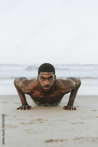 Cuadro en lienzo Fit man doing pushups in the sand