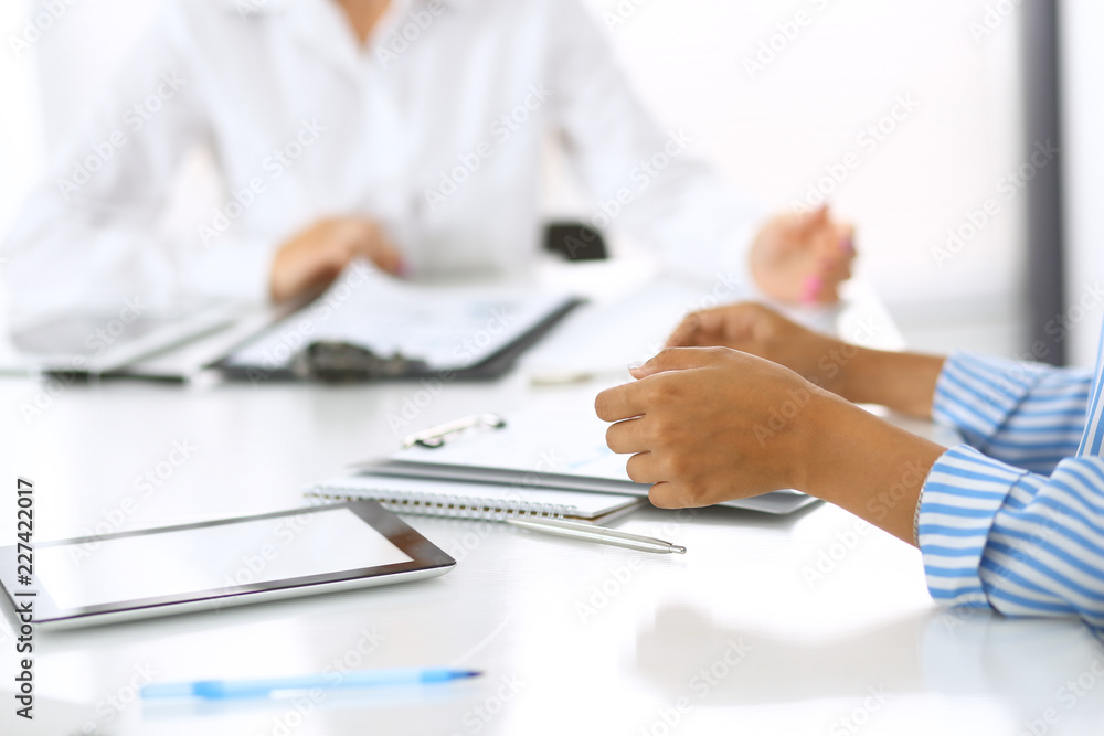 Group of business people at meeting in office, close-up. Team of two women discussing deal. Negotiation concept Group of business people at meeting in office, close-up. Team of two women discussing deal. Negotiation concept