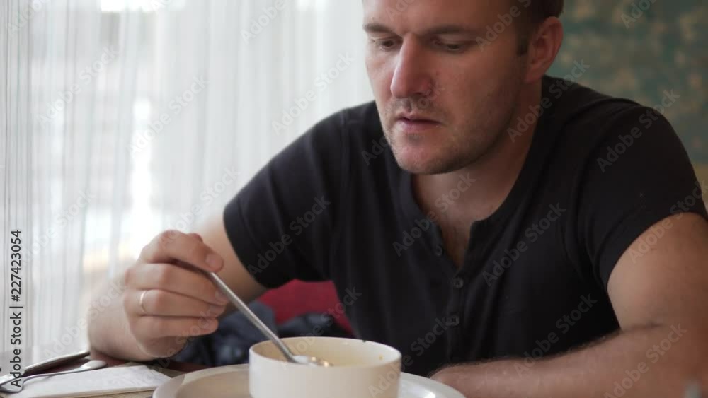 A man at a business lunch. Lunch break in the office. He quickly eats delicious hot soup from the plate. He sits at a table alone. A man at a business lunch. Lunch break in the office. He quickly eats delicious hot soup from the plate. He sits at a table alone.