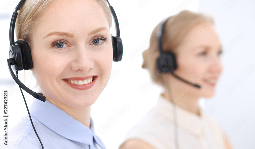 Bright call center office. Two blonde women in a headset Bright call center office. Two blonde women in a headset
