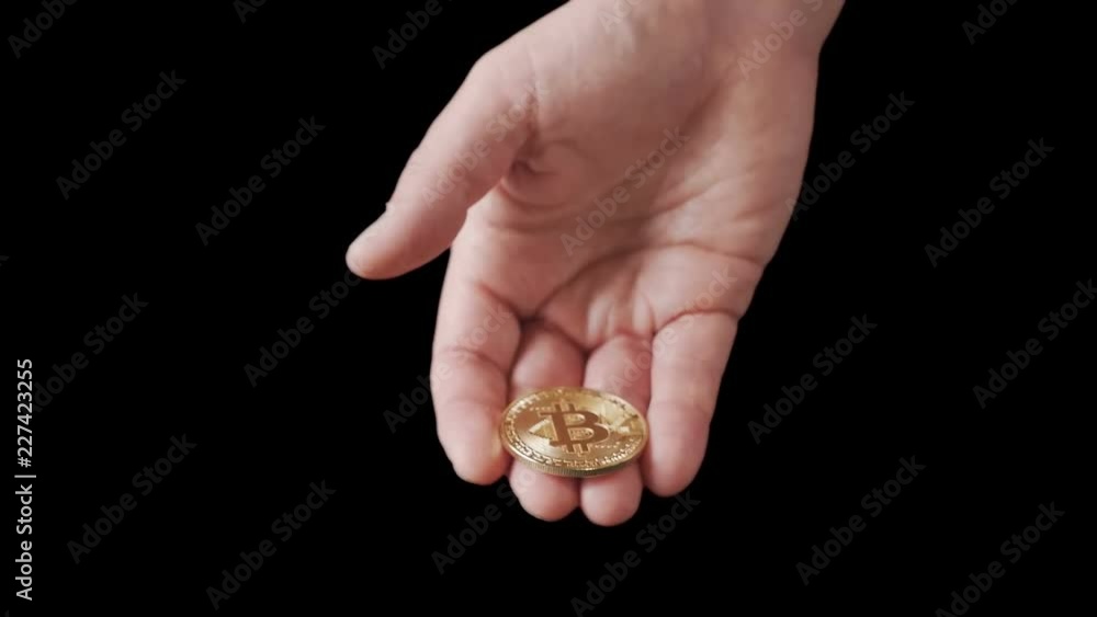 Male hand is holding a golden bitcoin cryptocurrency coin Male hand is holding a golden bitcoin cryptocurrency coin