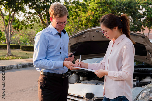 Insurance agent writing document on clipboard examining car after accident, Insurance concept