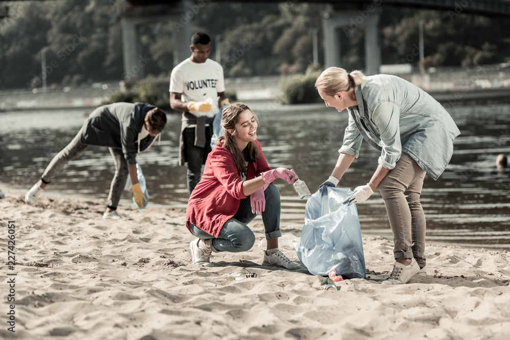Obraz premium Volunteer with children. Loving responsible mother feeling memorable while volunteering on the beach with her three children