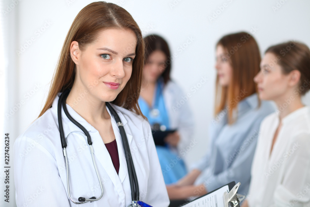Young beautiful female doctor smiling while consulting her patient. Physician at work. Medicine and healthcare concept Young beautiful female doctor smiling while consulting her patient. Physician at work. Medicine and healthcare concept