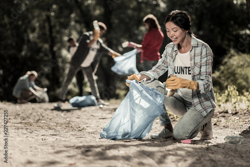 Cleaning forest. Beaming beautiful woman feeling extremely satisfied while cleaning up the forest volunteering
