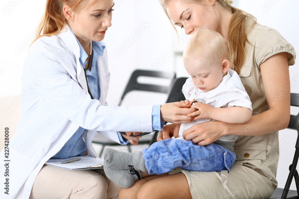 Obraz premium Doctor examining a little boy with stethoscope. Mother holds her son on her lap. Motherless and medicine concept