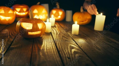 Human hands firing candles Halloween pumpkins on weathered wooden planks, no smoke, blue back light, sliding video