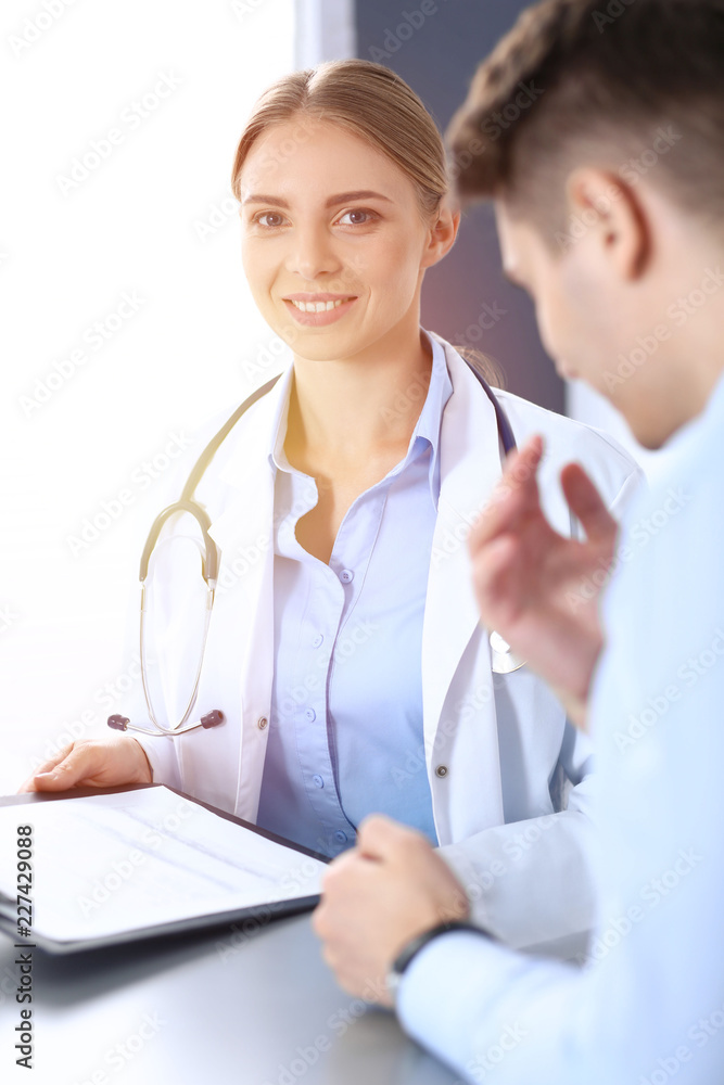 Doctor and patient in hospital. Beautiful blonde physician consulting business man about his health. Medicine concept Doctor and patient in hospital. Beautiful blonde physician consulting business man about his health. Medicine concept