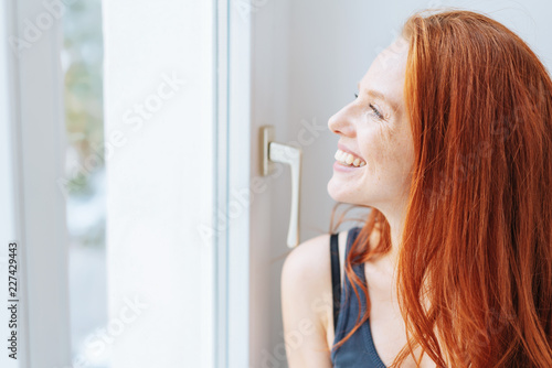 Smiling happy woman looking out of a window