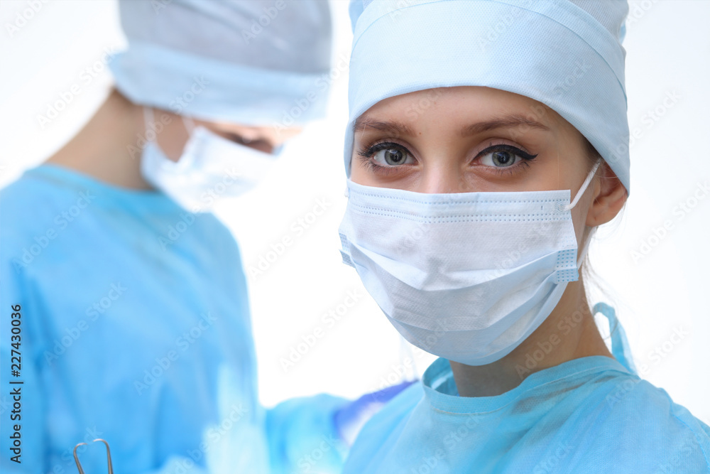 Surgeon doctor in mask performing operation. Focus on female intern girl. Medicine, emergency help concepts Surgeon doctor in mask performing operation. Focus on female intern girl. Medicine, emergency help concepts