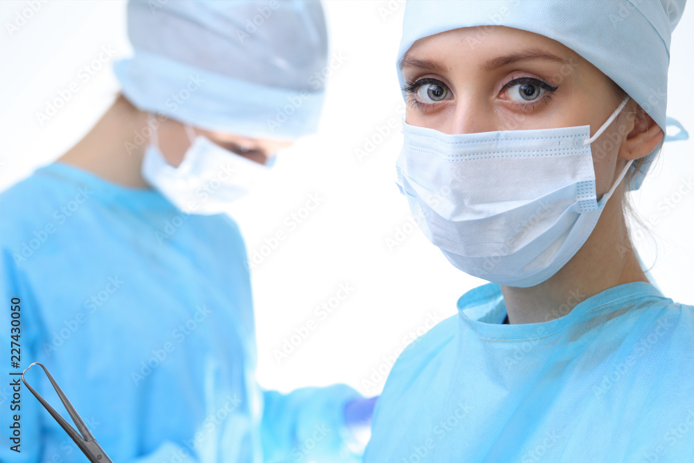 Surgeon doctor in mask performing operation. Focus on female intern girl. Medicine, emergency help concepts Surgeon doctor in mask performing operation. Focus on female intern girl. Medicine, emergency help concepts