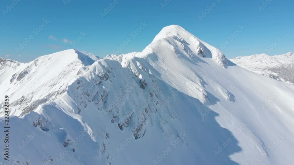 AERIAL: Cinematic shot of a majestic snowy mountain ridge in the picturesque sunny Alps. Flying along the breathtaking mountains covered in freshly fallen snow. Beautiful view of the wintry mountains. AERIAL: Cinematic shot of a majestic snowy mountain ridge in the picturesque sunny Alps. Flying along the breathtaking mountains covered in freshly fallen snow. Beautiful view of the wintry mountains.