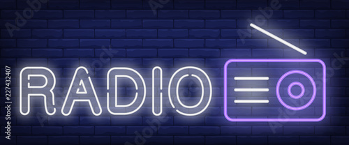 Radio neon sign. Receiver with antenna on brick wall background. Vector illustration in neon style for radio station and broadcasting