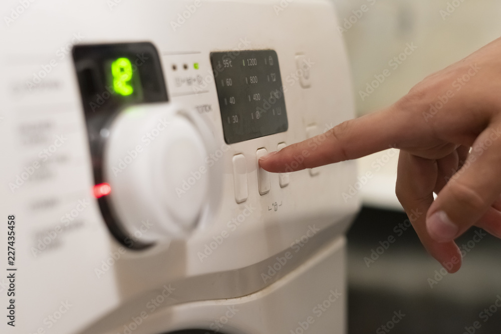 close up hand pushing the button to start the washing machine f close up hand pushing the button to start the washing machine f